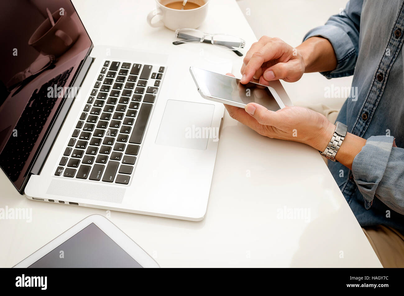 L'uomo utilizza lo smartphone alla scrivania in ufficio. Foto Stock