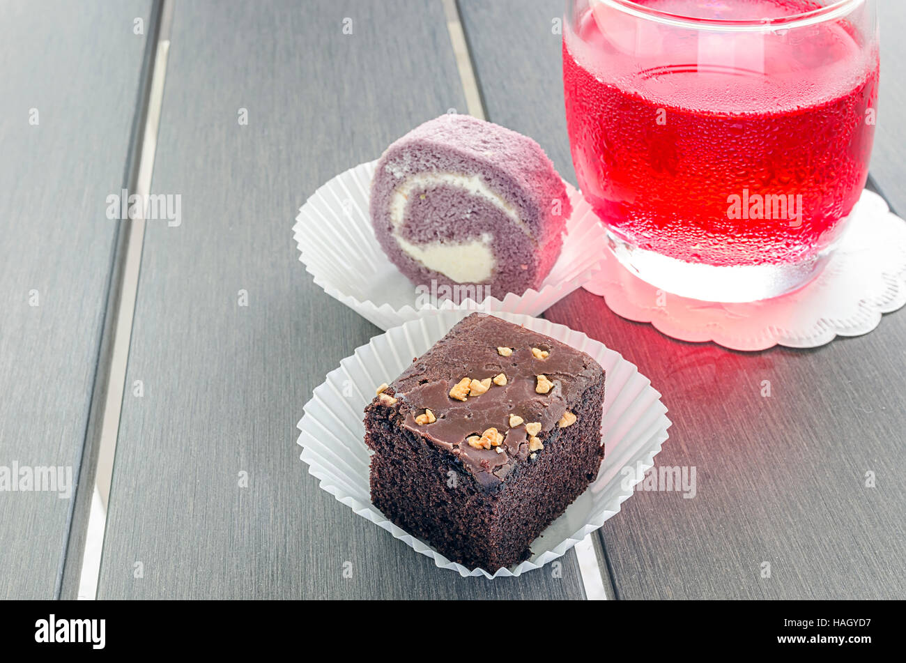 In casa brownie al cioccolato o torte al cioccolato con noci e la torta sul rotolo di carta bianca tazza sul tavolo di legno. Foto Stock
