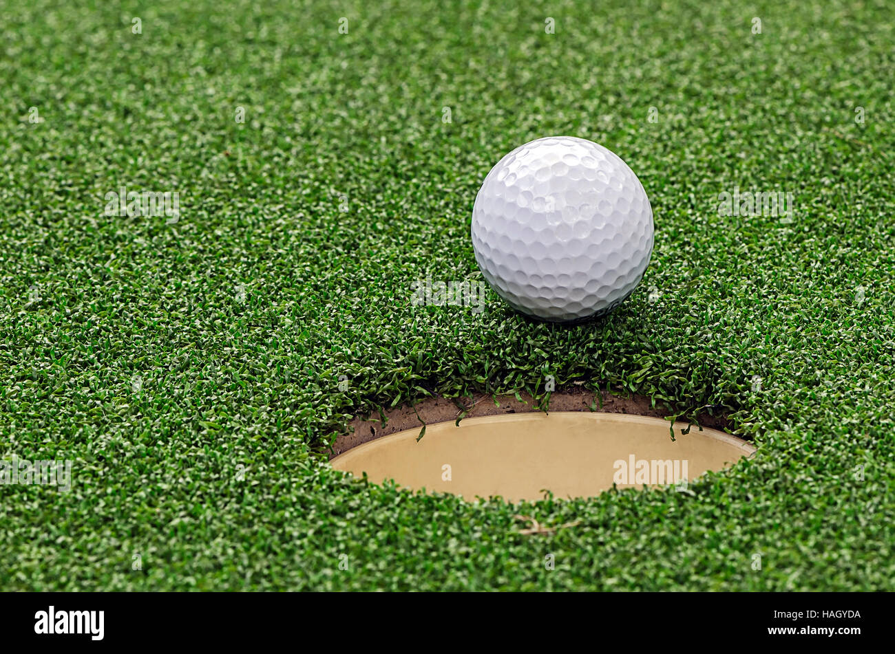 Palla da golf sul labbro della tazza,vista ravvicinata. Foto Stock