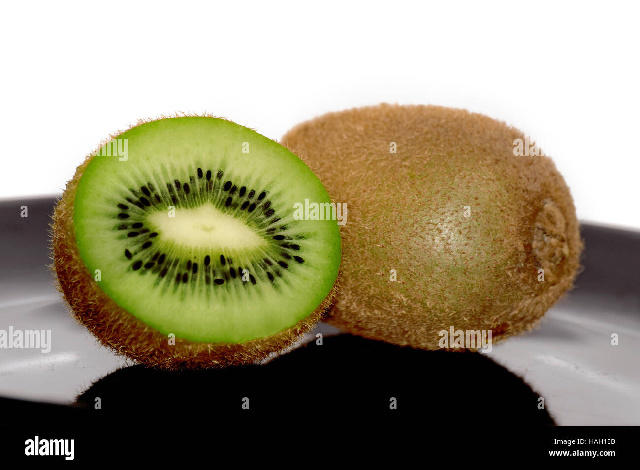 L'uno e metà kiwi sulla piastra nera Foto Stock