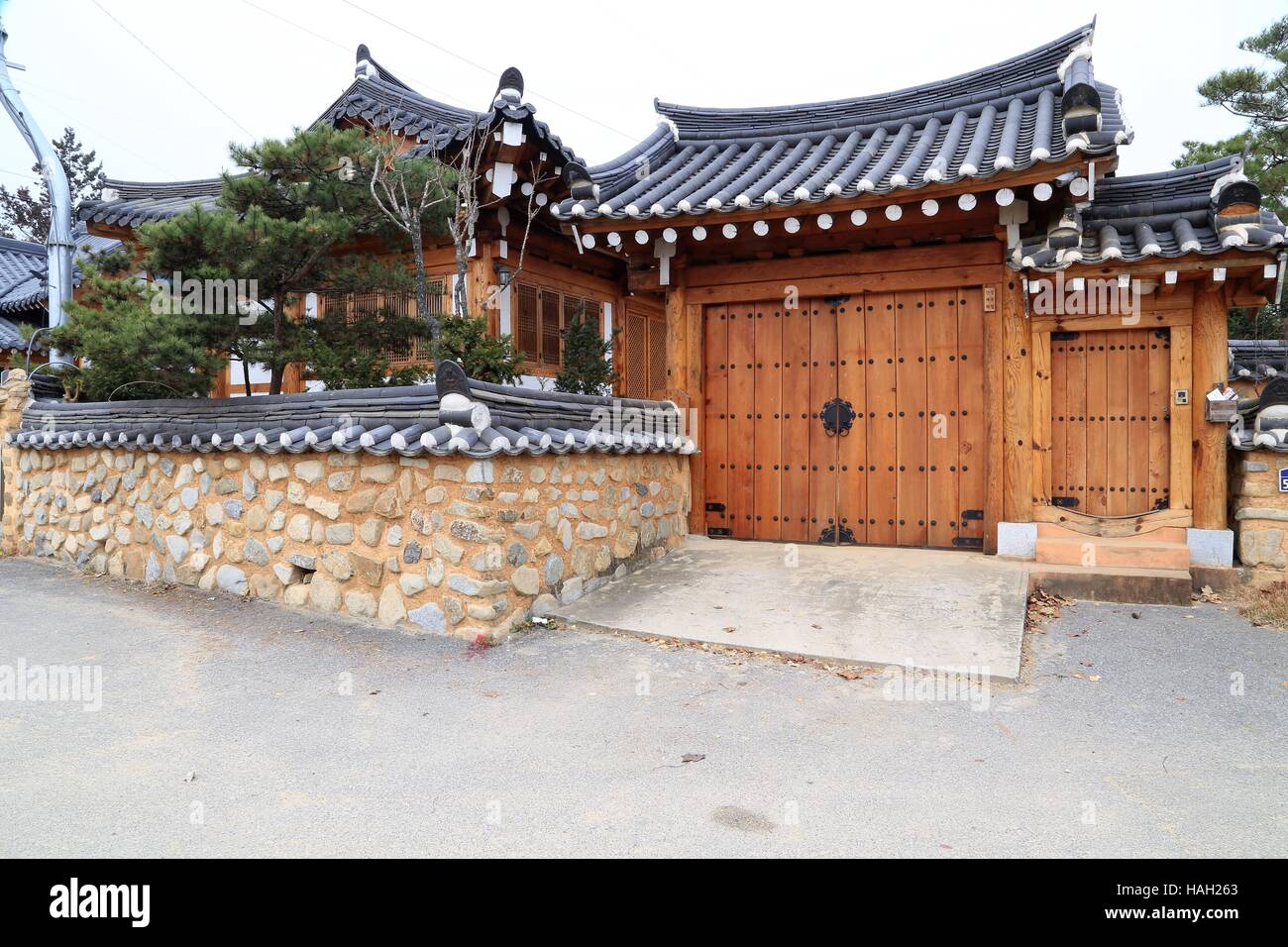 Tetto in tegole gateway in nuova costruzione di stile antico. Il coreano piastrelle nere tetto con pesanti porte di legno. Foto Stock