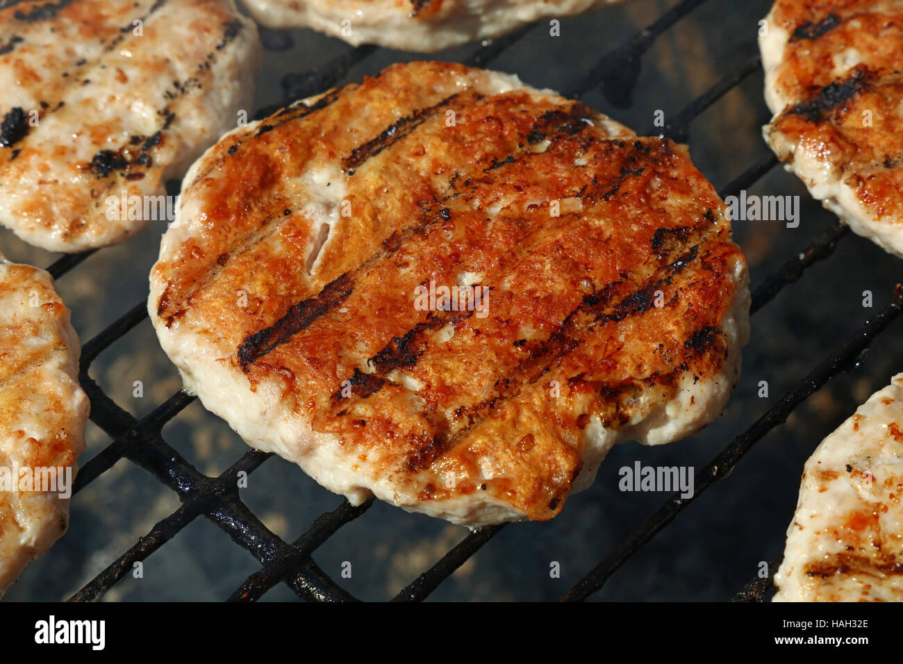 Un pollo o tacchino pollame carni grigliate barbecue burger per hamburger preparati sul fumo barbecue grill, close up Foto Stock
