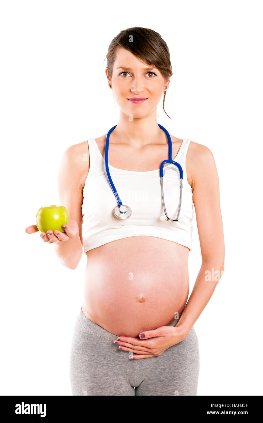 Donna incinta con uno stetoscopio e Apple. Pancia in gravidanza isolato su bianco. Foto Stock