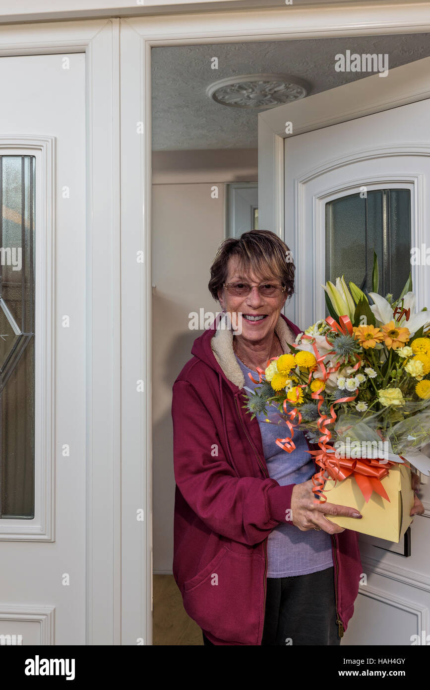 Senior lady accettando una consegna fiori sulle madri di giorno o di compleanno. Foto Stock