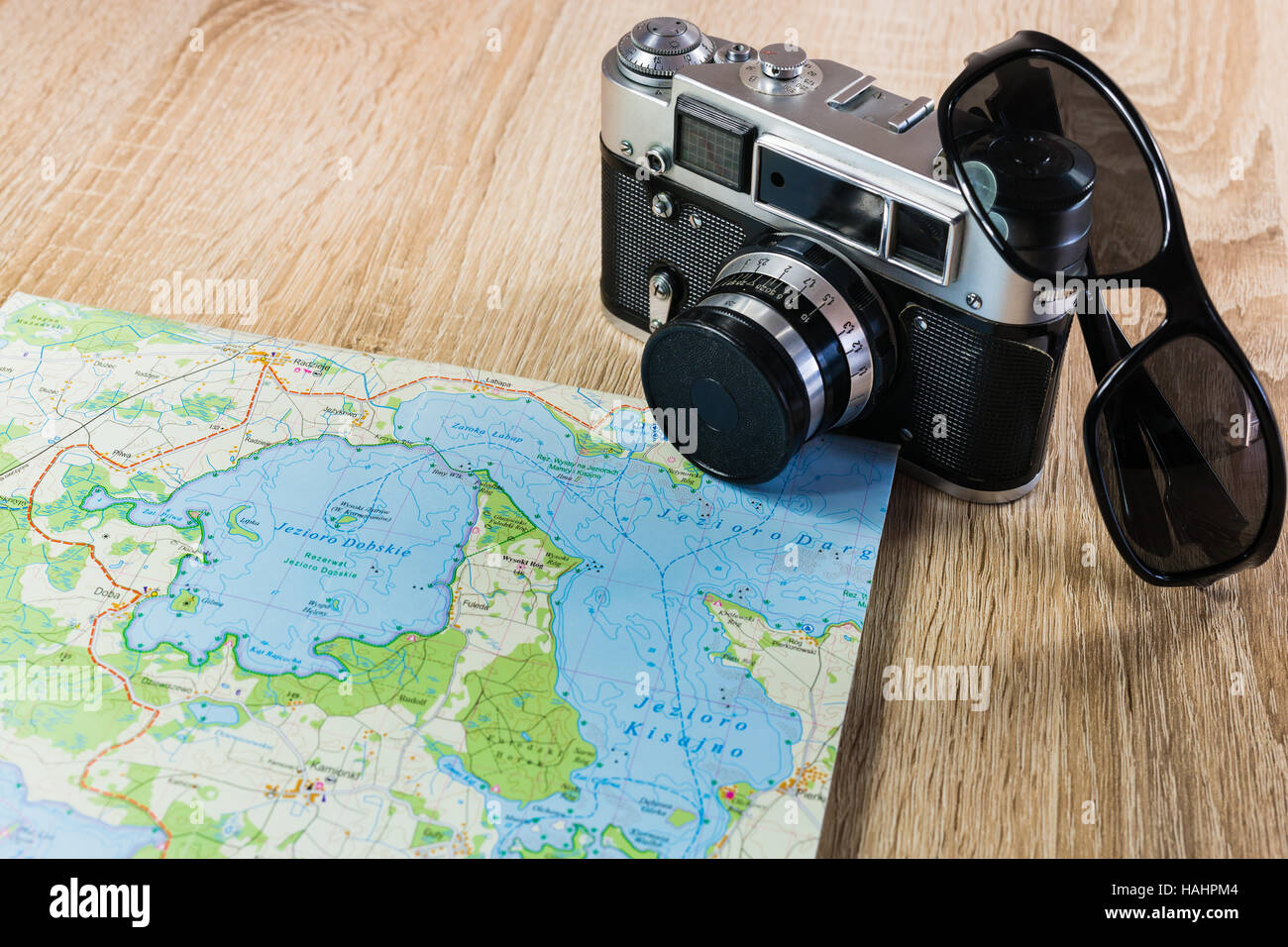 Vecchia macchina fotografica su una mappa di laghi in Polonia. Fotocamera obsoleta su una mappa. Occhiali da sole nei pressi della vecchia telecamera. Foto Stock