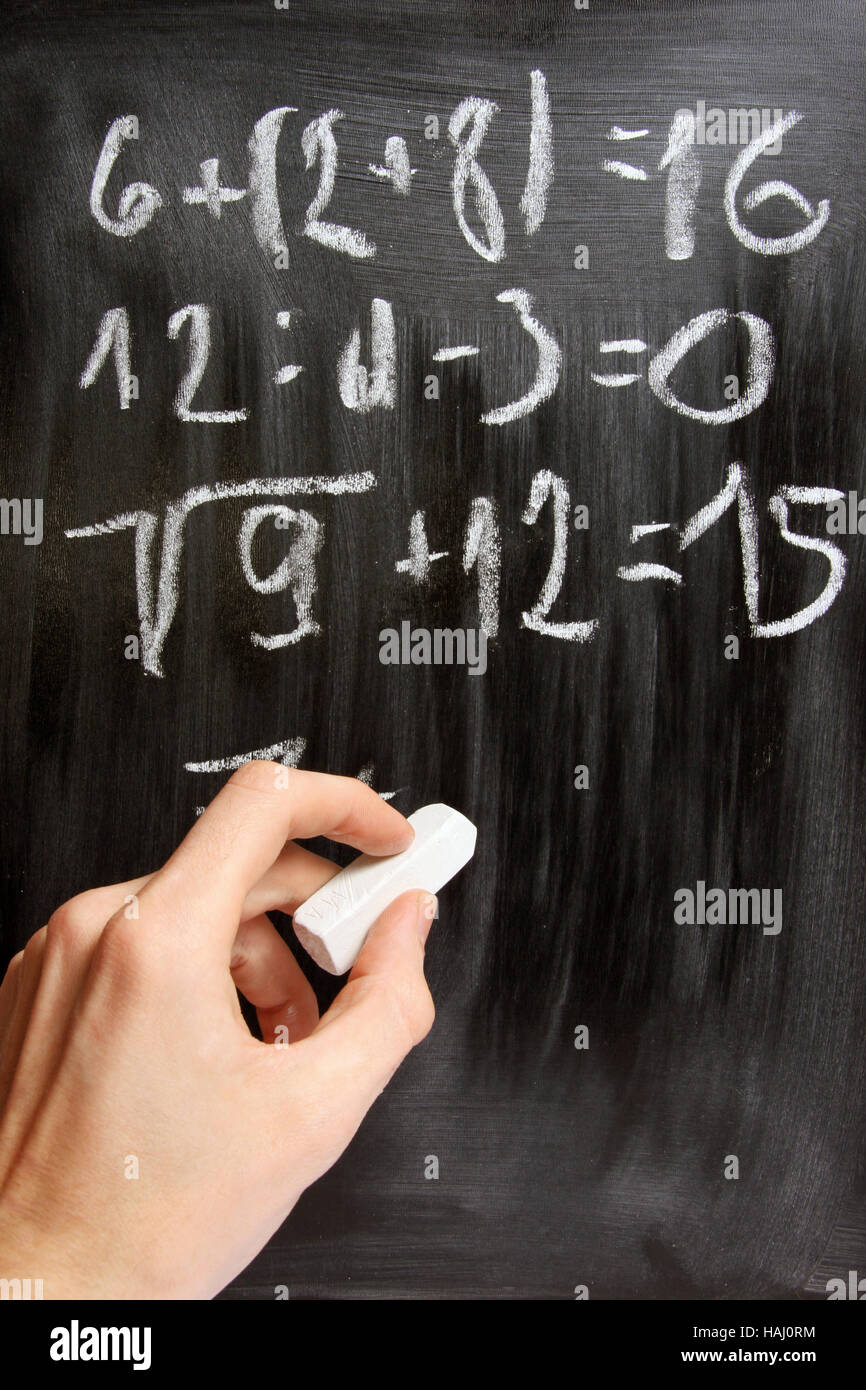 Scrive a mano equazioni matematiche sulla lavagna nera Foto Stock