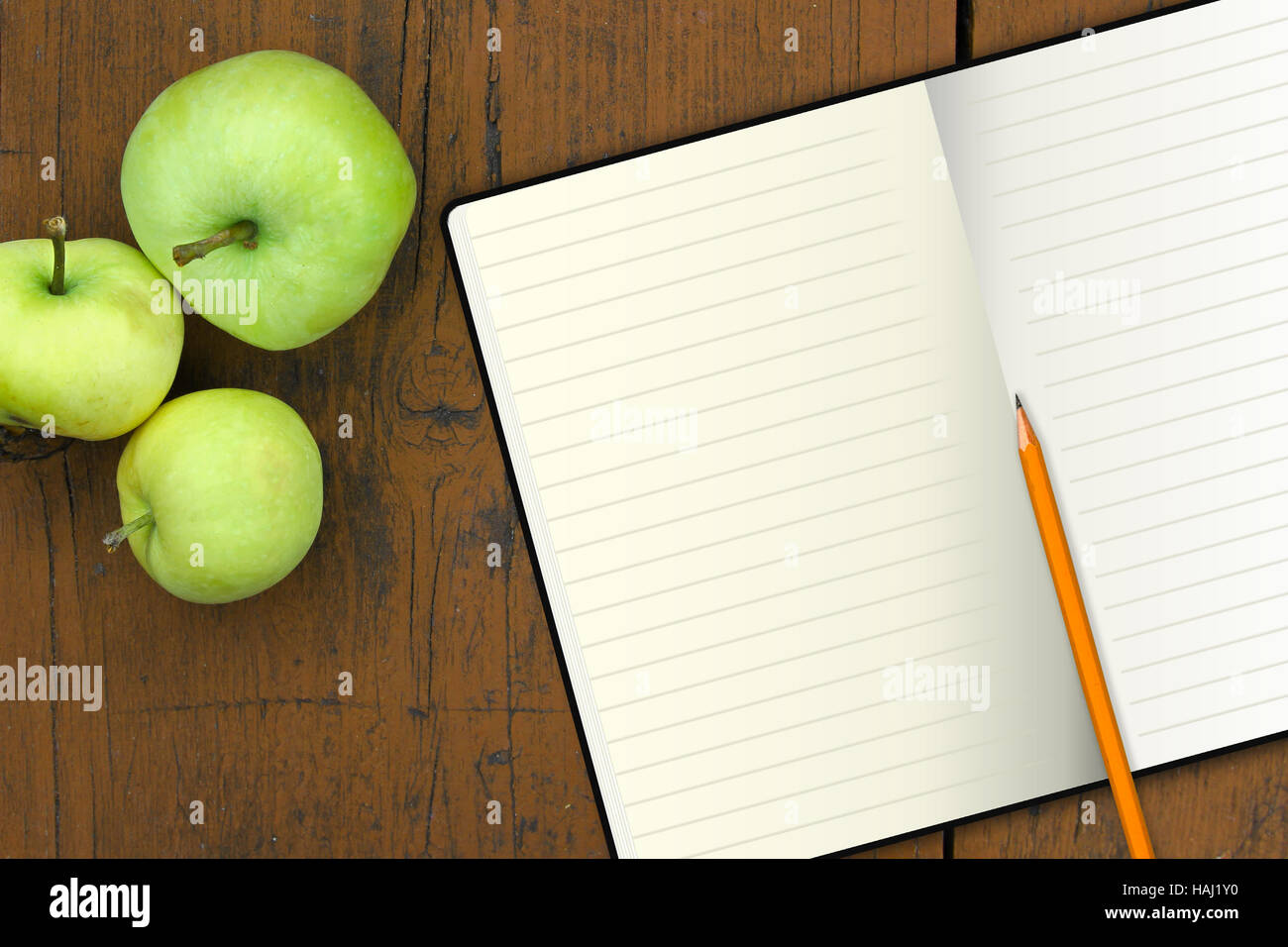 Notebook con matita e mele su una tavola di legno Foto Stock