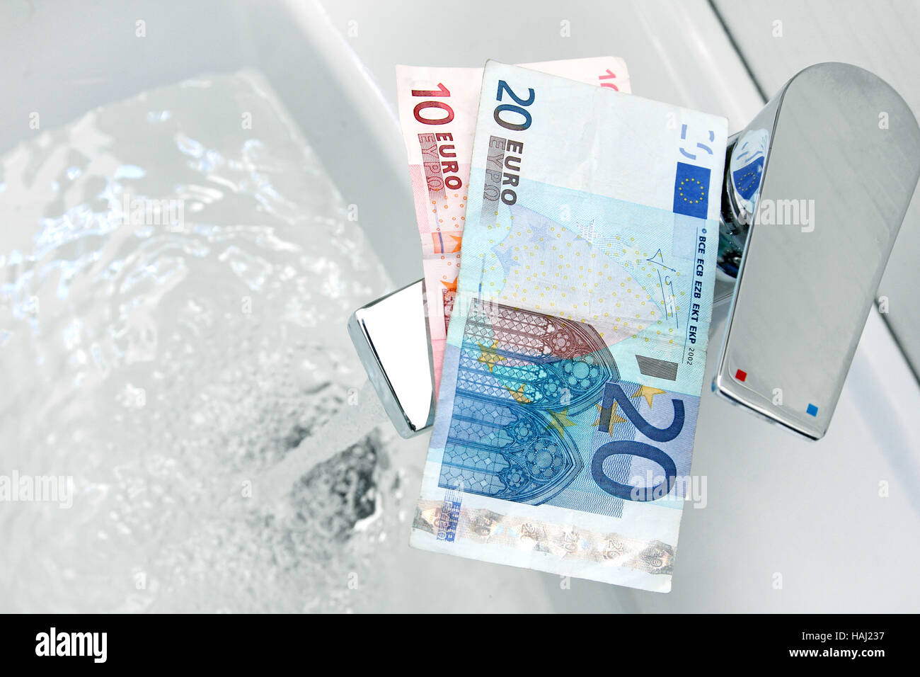 Euro denaro sul rubinetto e acqua corrente Foto Stock