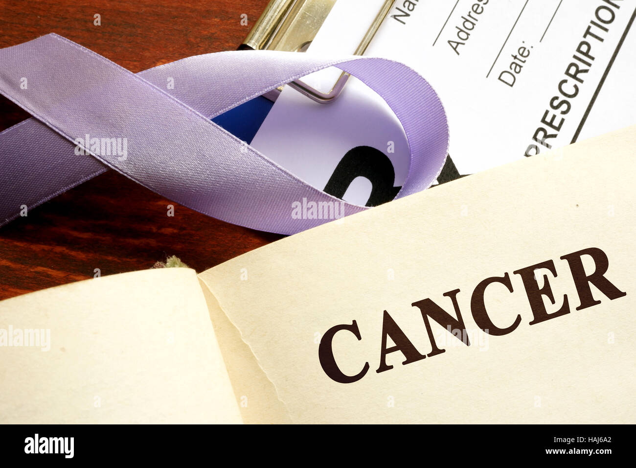 Il cancro scritto su una pagina e la consapevolezza di lavanda nastro. Foto Stock