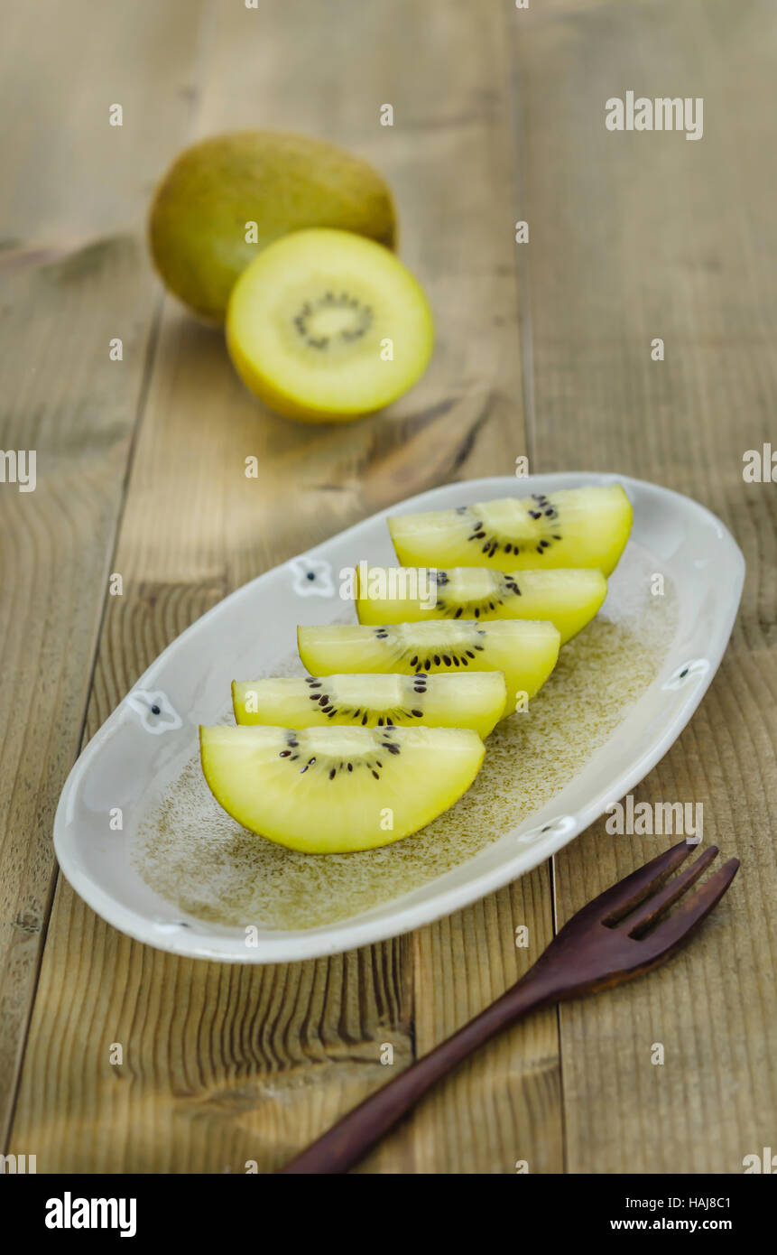 Golden kiwi e affettato sul piatto su sfondo di legno Foto Stock