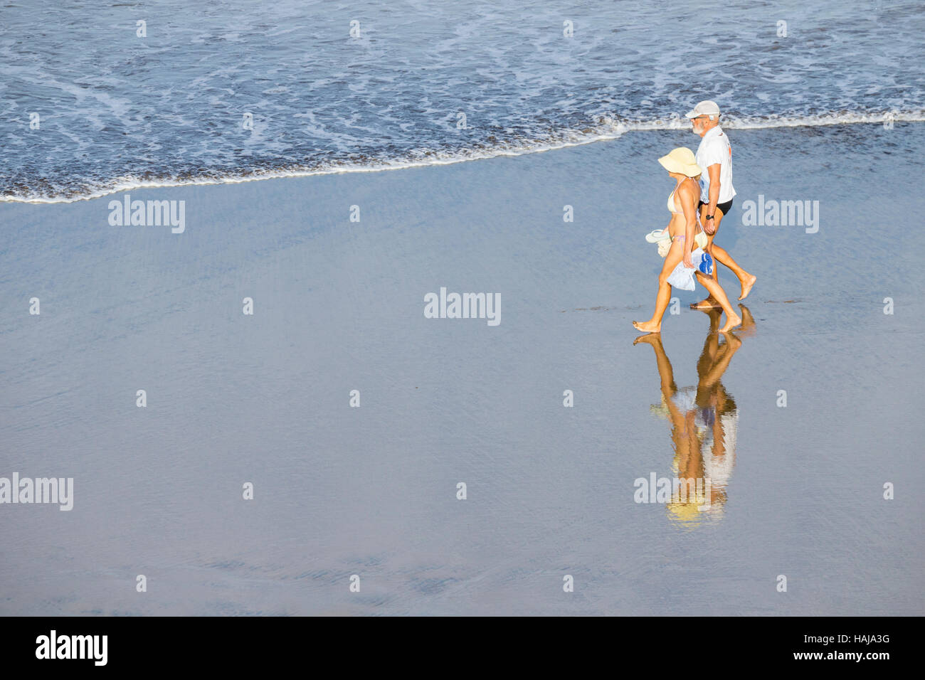 Coppia di anziani camminando sulla spiaggia in Spagna Foto Stock
