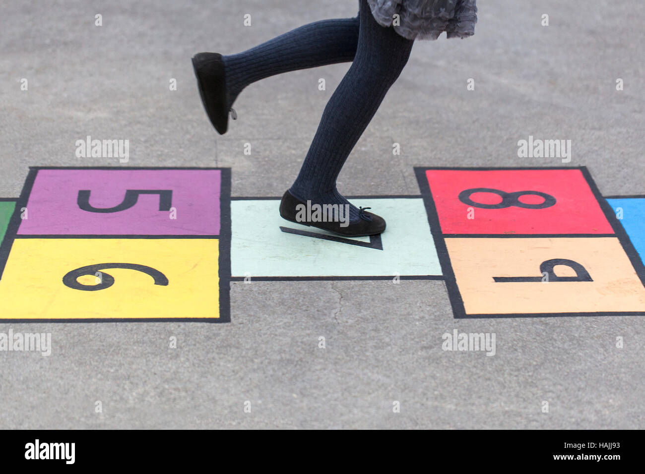 Ragazza giocando ho un coloratissimo gioco campana dipinta sul marciapiede Foto Stock