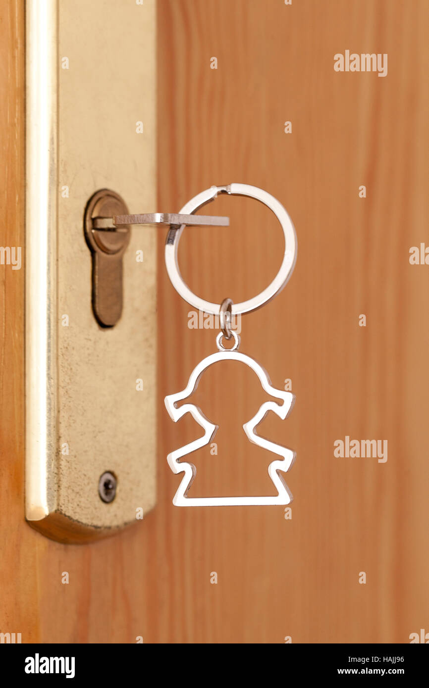 Portachiavi con una forma femminile nella serratura di una porta di ingresso Foto Stock
