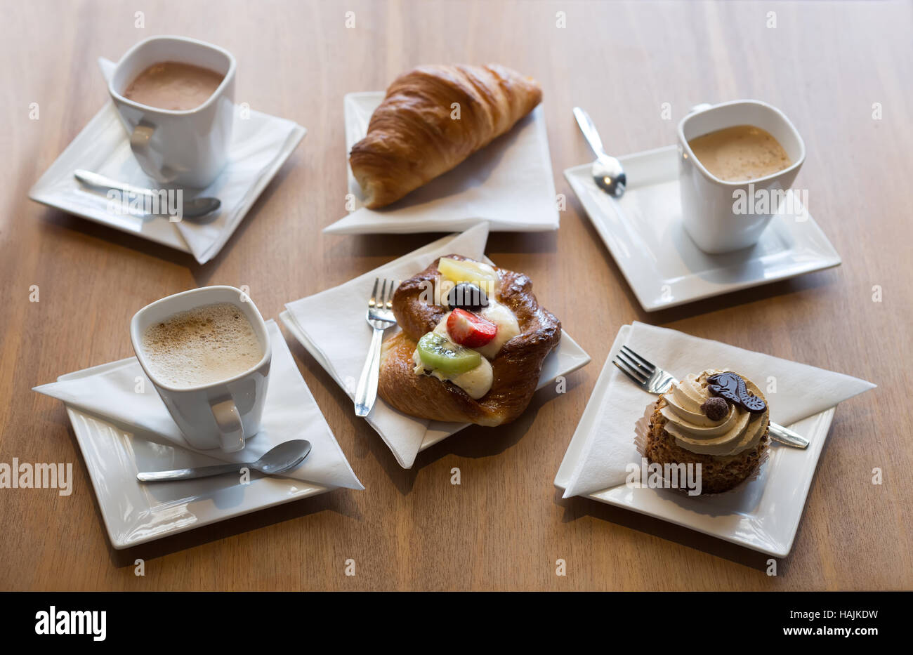 Ancora in vita. Tre tazze di caffè, croissant e pasticcini. Su un tavolo di legno. Foto Stock