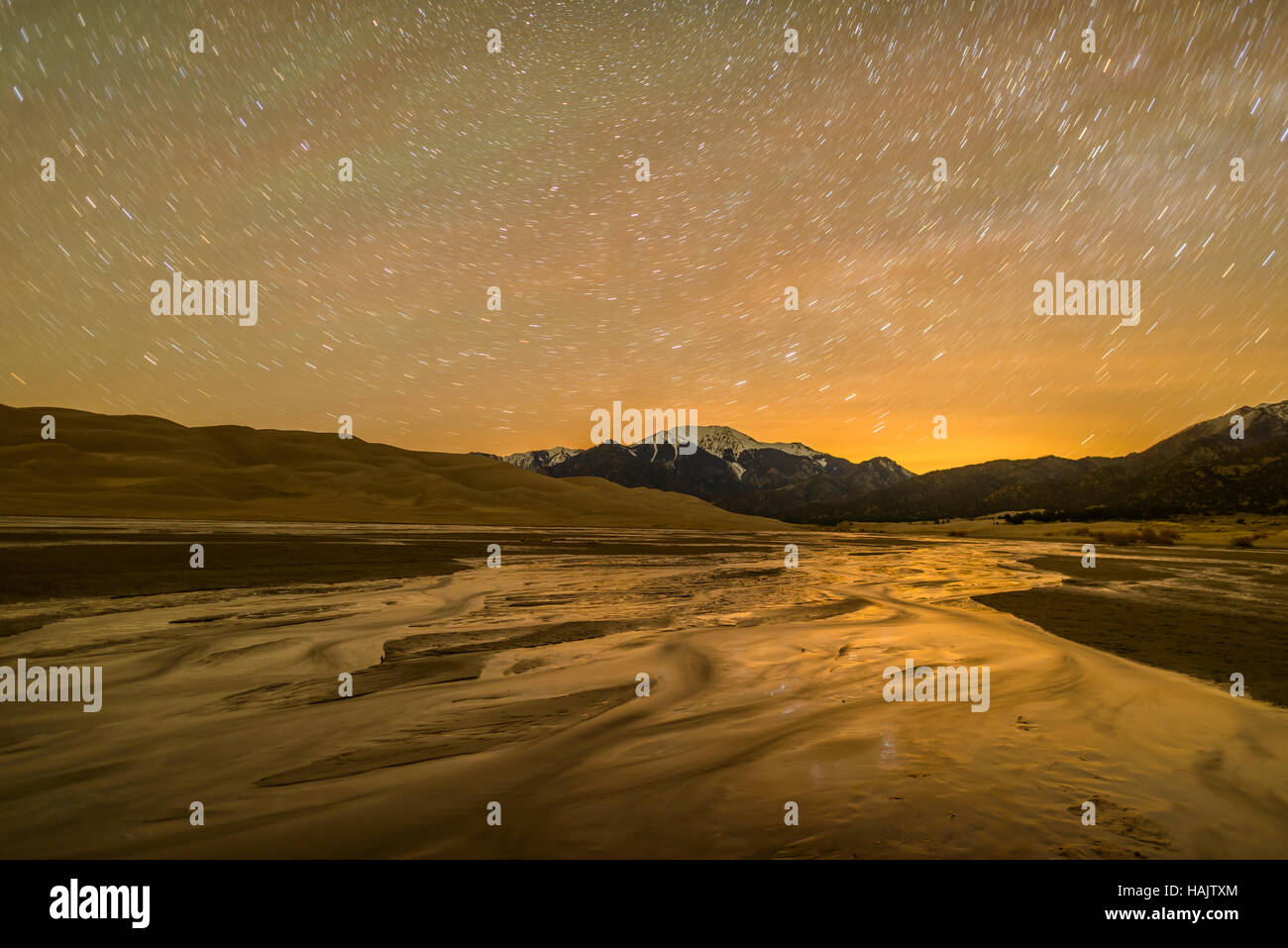 Notte di primavera a grandi dune di sabbia del Parco Nazionale - una lunga esposizione cattura tracce stellari nel cielo notturno sopra la molla Medano Creek. Foto Stock