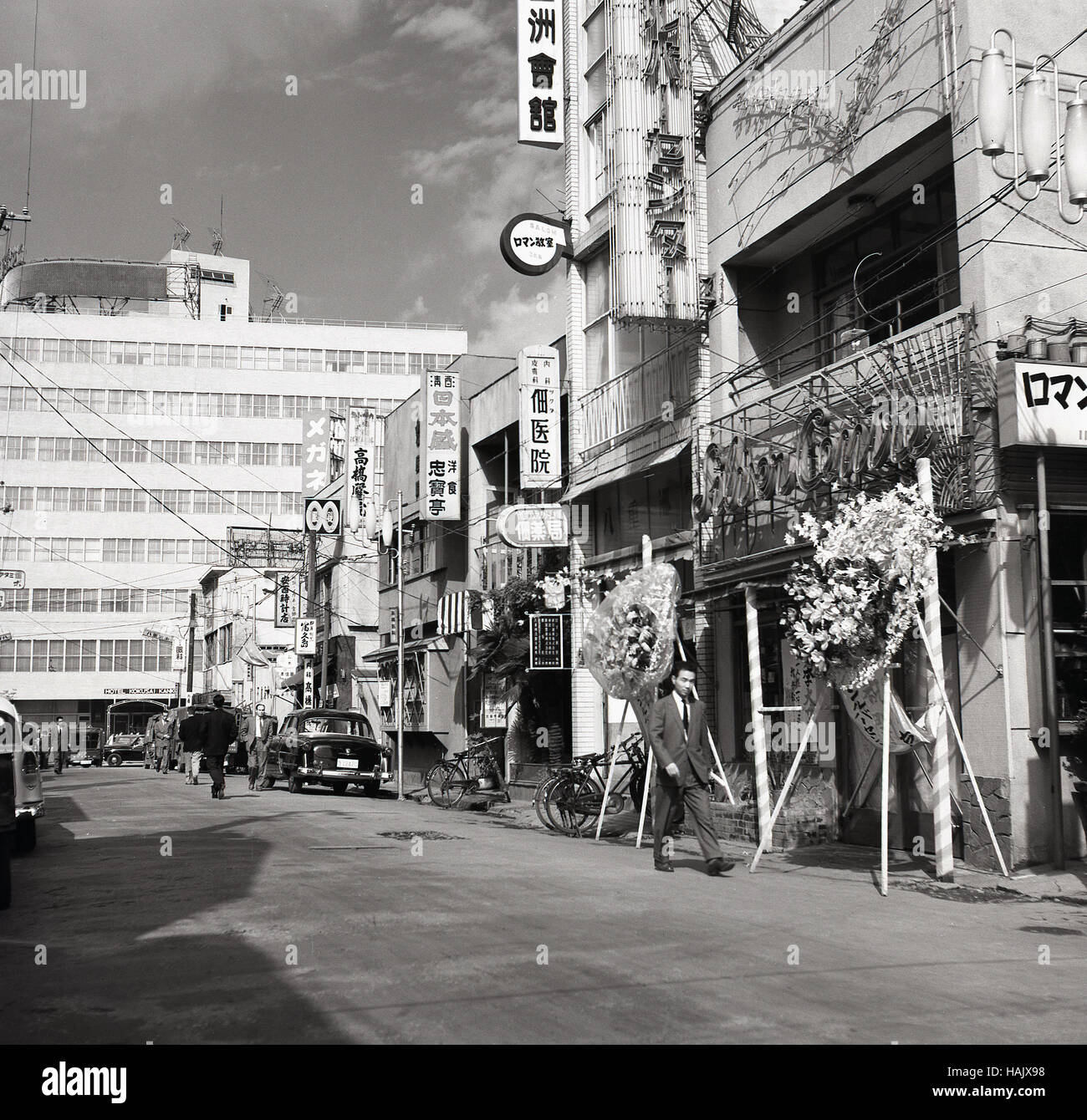 Anni '1950, storico, esterno di un negozio al piano terra, nella città vecchia di Tokyo, Giappone. Una grande esposizione di fiori all'esterno di un negozio. Foto Stock