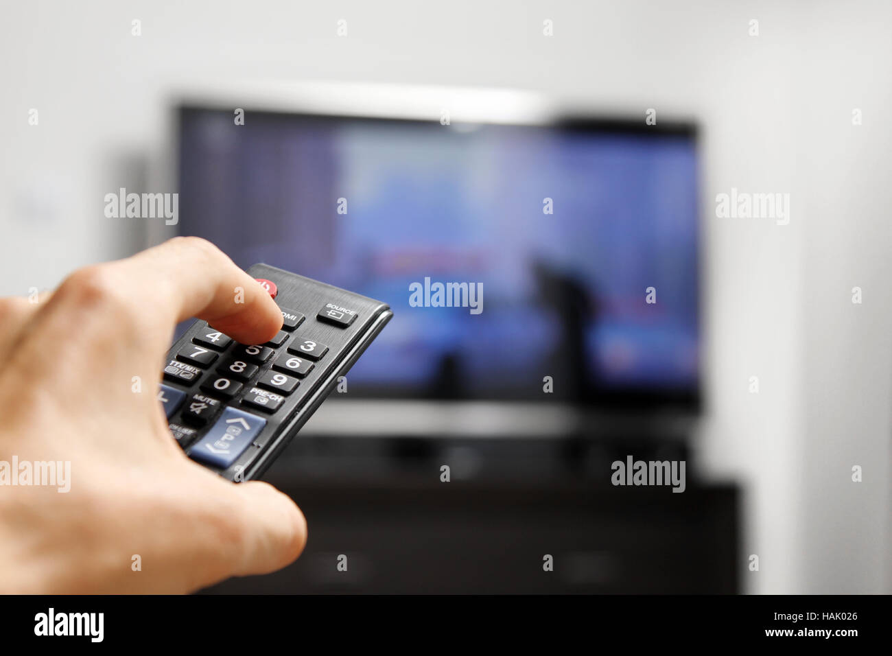 Tenere in mano il telecomando nella parte anteriore della tv Foto Stock