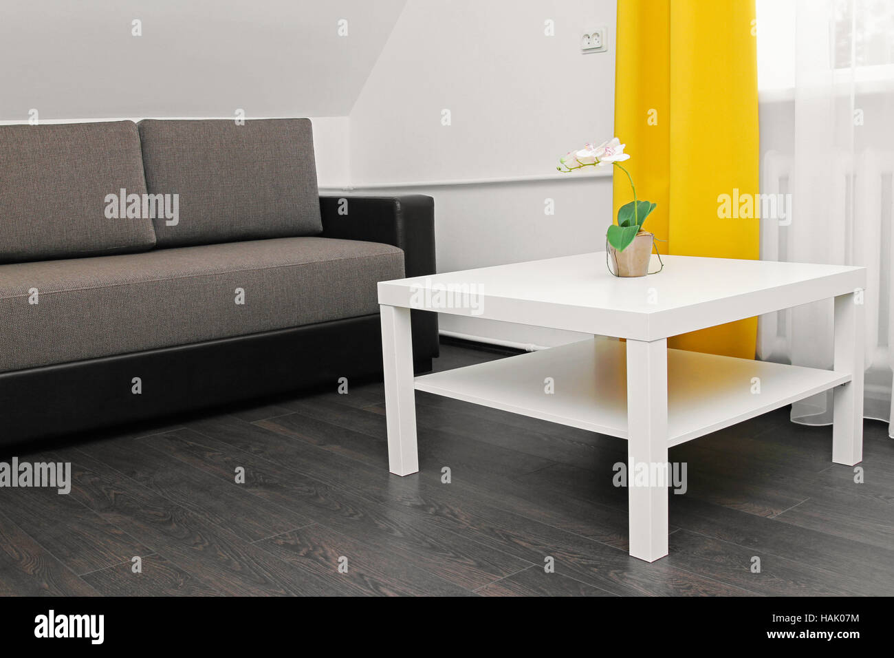 Appartamento luminoso interno con divano, tavolino da caffè e tende gialle Foto Stock
