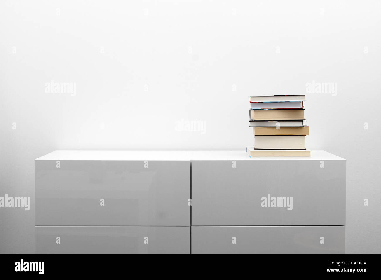Comò bianco con la pila di libri in minimalismo luminoso interno Foto Stock