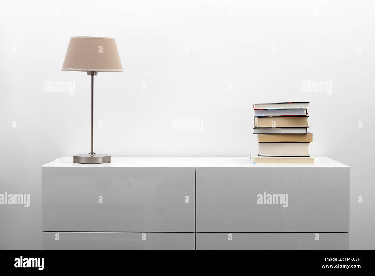 Comò bianco con lampada e libri di minimalismo luminoso interno Foto Stock