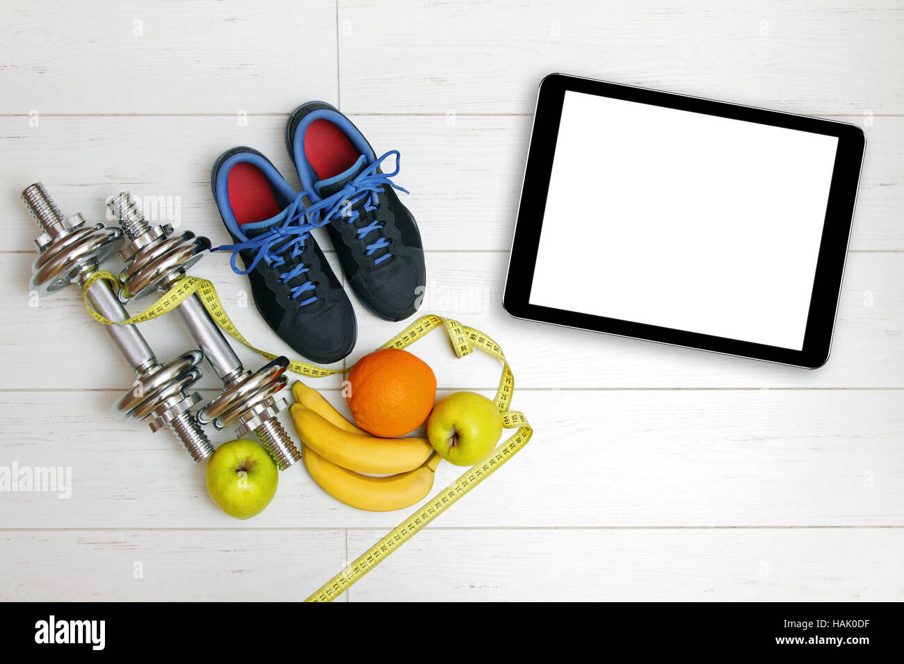 Attrezzature per il fitness, frutta e fustellato tavoletta digitale su bianco pavimento in legno Foto Stock
