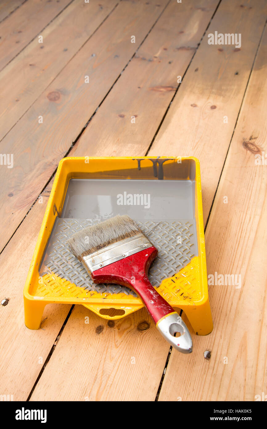 Tavola in legno del pavimento. verniciatura vernice grigio e il pennello nel vassoio Foto Stock