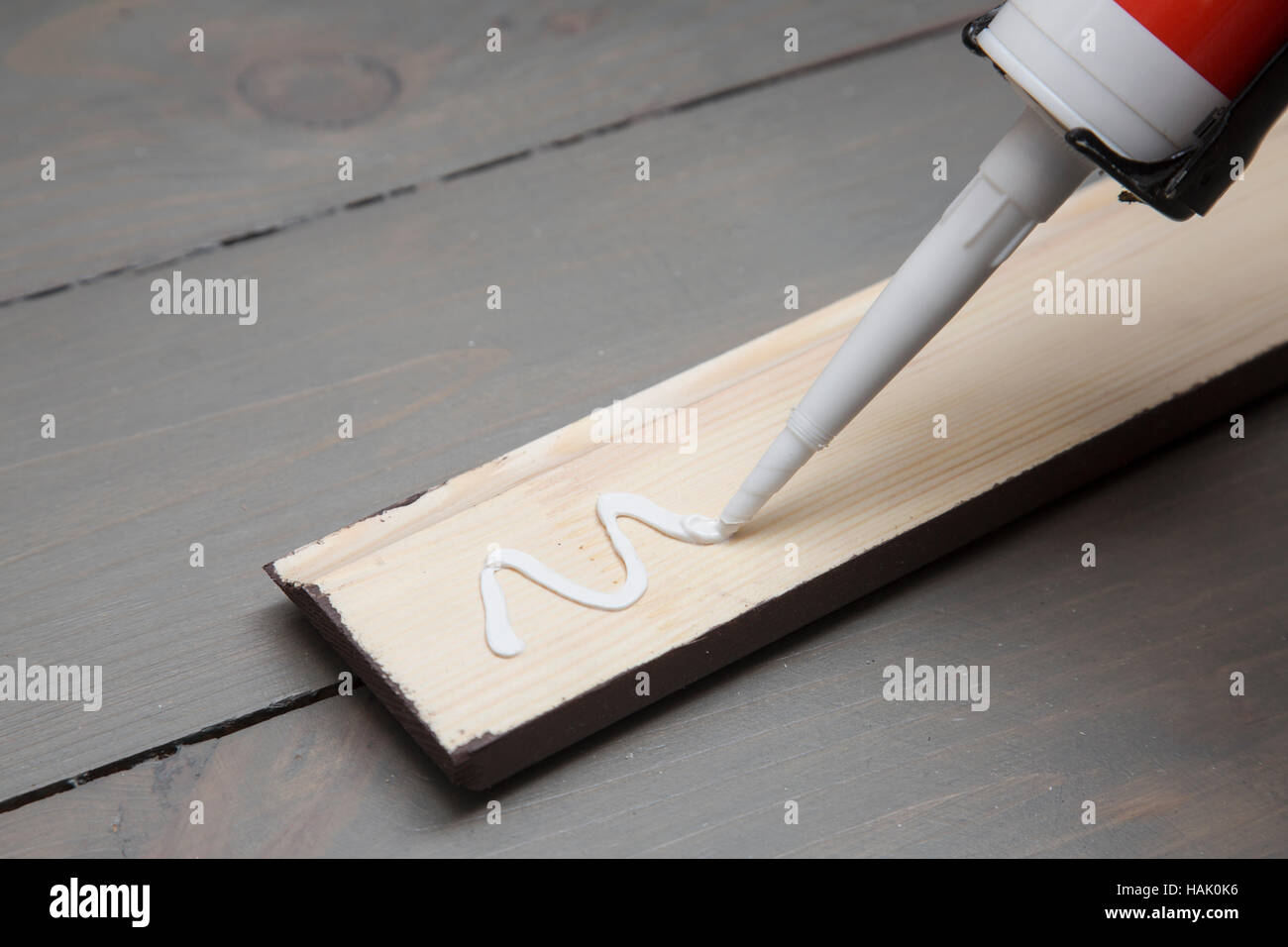 Mettere la colla su un pezzo di zoccolo di legno Foto Stock