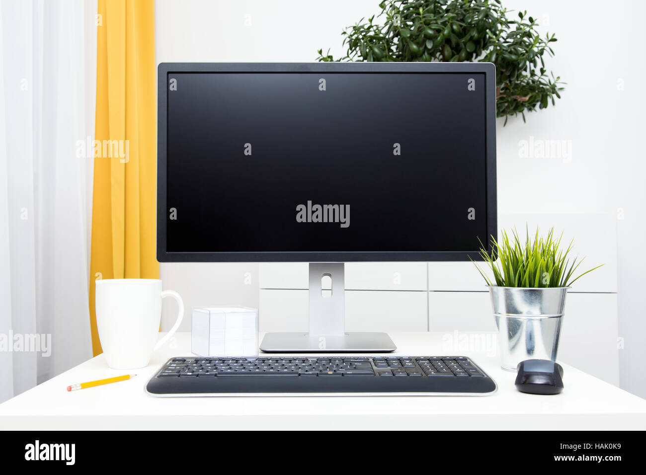 Monitor in bianco e accessori per ufficio sul tavolo in interni luminosi Foto Stock