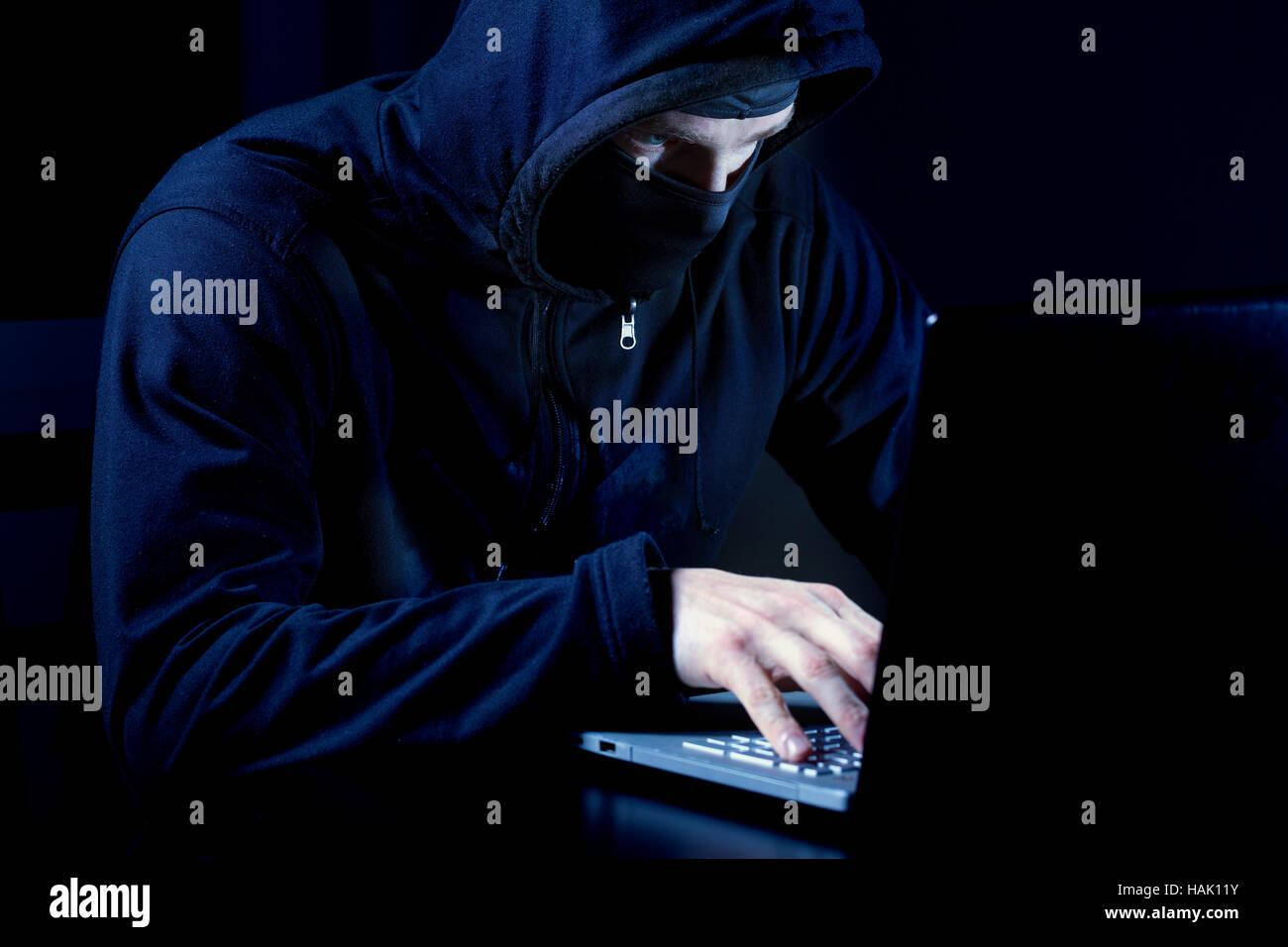 Hacker con maschera utilizzando il computer portatile Foto Stock