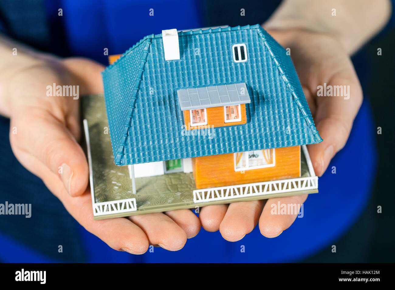 Immobiliare di concetto - piccole dimensioni modello casa di famiglia a womans mani Foto Stock