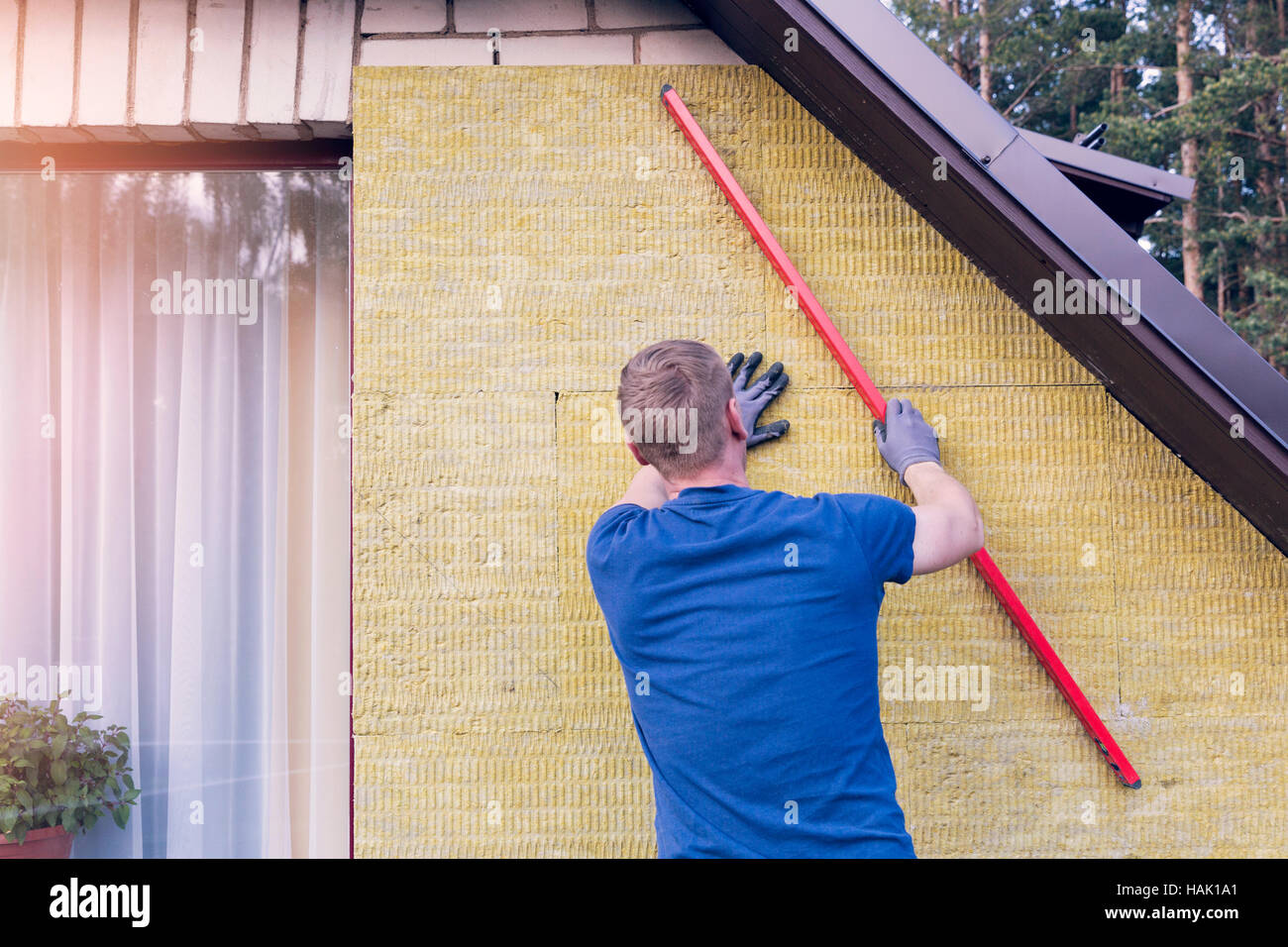 Operaio edile controlla il livello di casa isolata parete Foto Stock