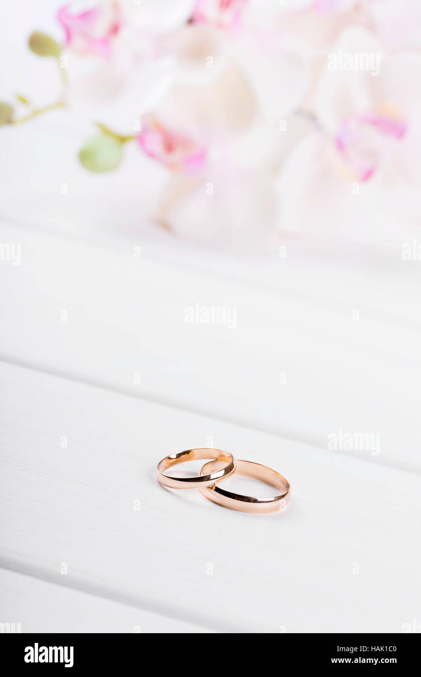 Nozze d'oro anelli con fiori di colore bianco sul tavolo di legno Foto Stock