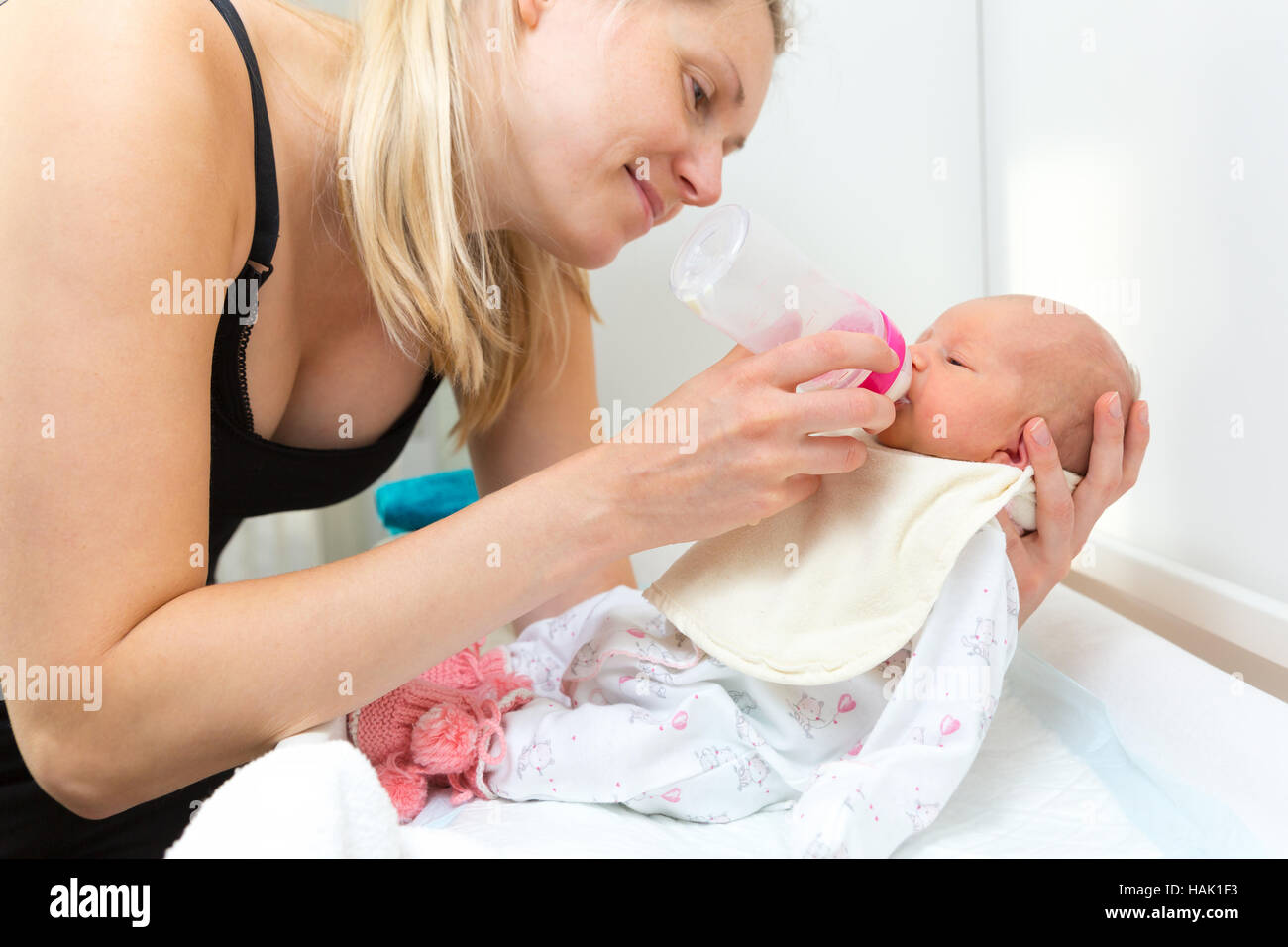 Felice madre alimenta il loro bambino neonato con bottiglia Foto Stock