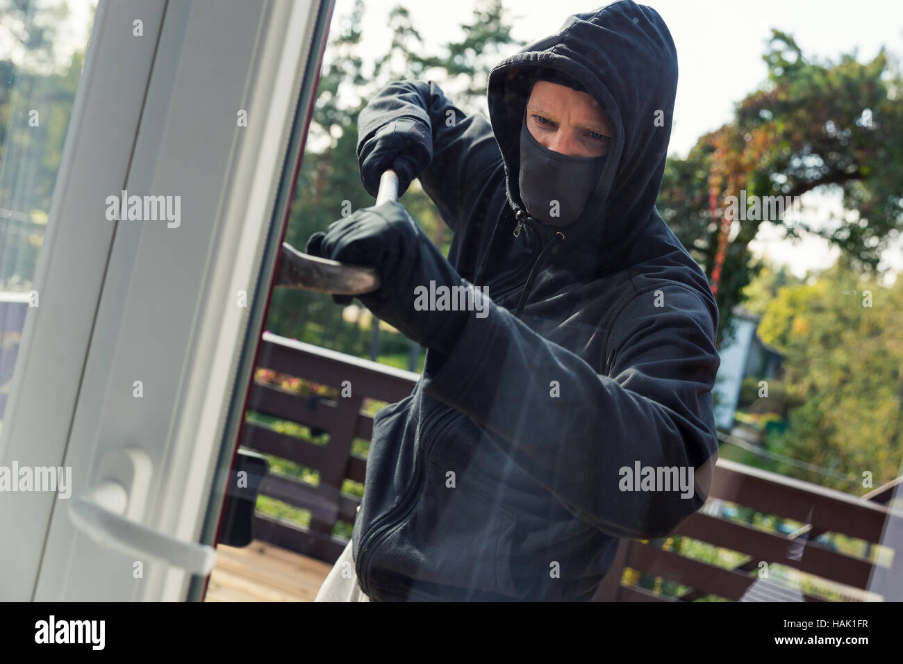 Rapina in casa - ladro apre le porte del balcone con palanchino Foto Stock