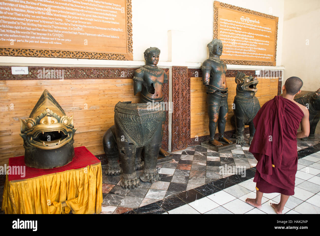 Statue in bronzo di Angkor Wat Tempio del Buddha Mahamuni Mandalay // MANDALAY, Myanmar - Un museo esposto al Tempio del Buddha Mahamuni espone statue in bronzo originarie di Angkor Wat in Cambogia, con un cartello informativo che illustra il loro complesso viaggio storico. Le figure in bronzo furono prese da Angkor Wat ad Ayutthaya nel 1431, poi portate in Myanmar da vari governanti attraverso secoli di conquista e sconvolgimenti politici. Durante il regno di re Bodawpaya, il principe ereditario Thado Minsaw trasportò questi manufatti insieme alla famosa immagine del Buddha Mahamuni dal regno di Arakan nel 1784-1785. Il Foto Stock