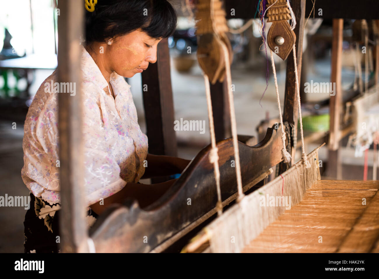 Tessitura Traditional Loom Woman Minnanthu Myanmar // MINNANTHU, Myanmar — Una donna utilizza un telaio tradizionale per tessere tessuti nel villaggio di Minnanthu, situato nella zona archeologica di Bagan nel Myanmar centrale. Il villaggio si trova tra le antiche rovine del tempio della zona archeologica di Bagan, che contiene oltre 2.000 templi buddisti e pagode risalenti all'XI-XIII secolo. Il villaggio di Minnanthu conserva artigianato tradizionale e stili di vita nonostante sia circondato da uno dei siti archeologici più significativi del Myanmar. La pianura di Bagan, situata lungo il fiume Ayeyarwady (anche kno Foto Stock
