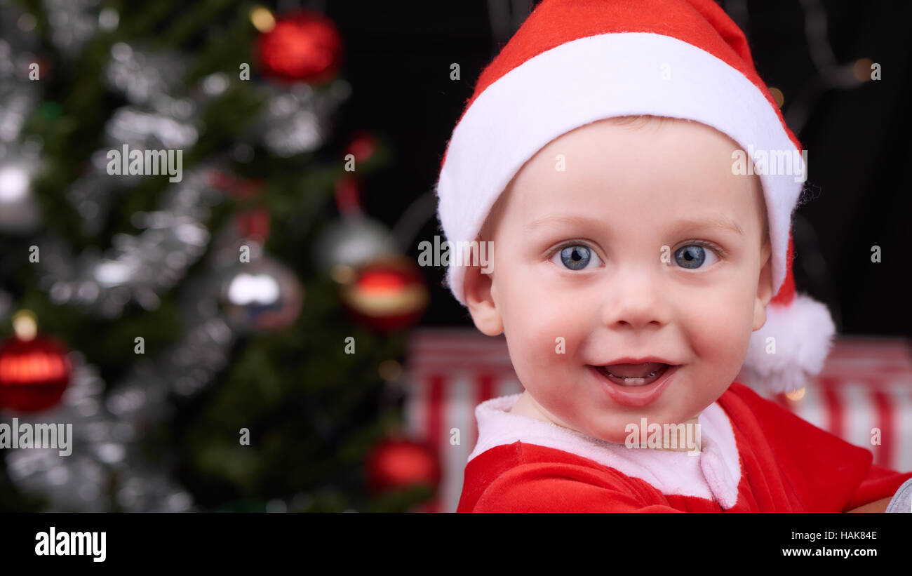 Baby boy sorridendo allegramente in telecamera in santa clausola outfit Foto Stock