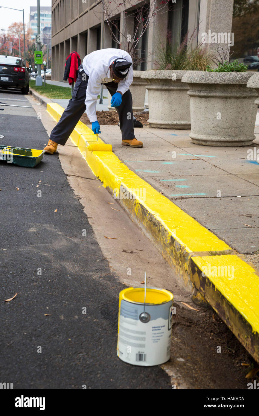 Washington, DC - un lavoratore dipinge il no-area di parcheggio del cordolo giallo su una strada della citta'. Foto Stock