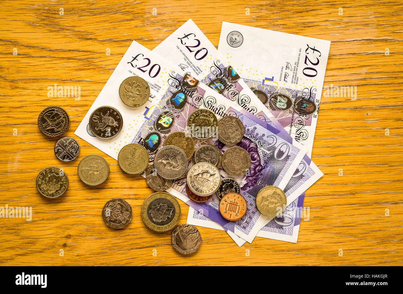 Contanti in forma di monete in inglese e moneta note su una tavola di pino Foto Stock