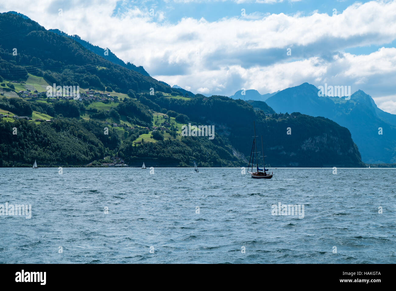 La vista mozzafiato sul lago con barche su di esso e le montagne sullo sfondo in Svizzera Foto Stock
