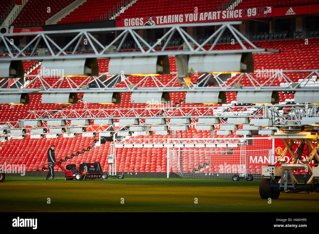 Lo stadio del Manchester United groundsman aerare la macchina di erba prato passo delle luci artificiali manutenzione giardinaggio gardner personale lavoro soccer football spor Foto Stock