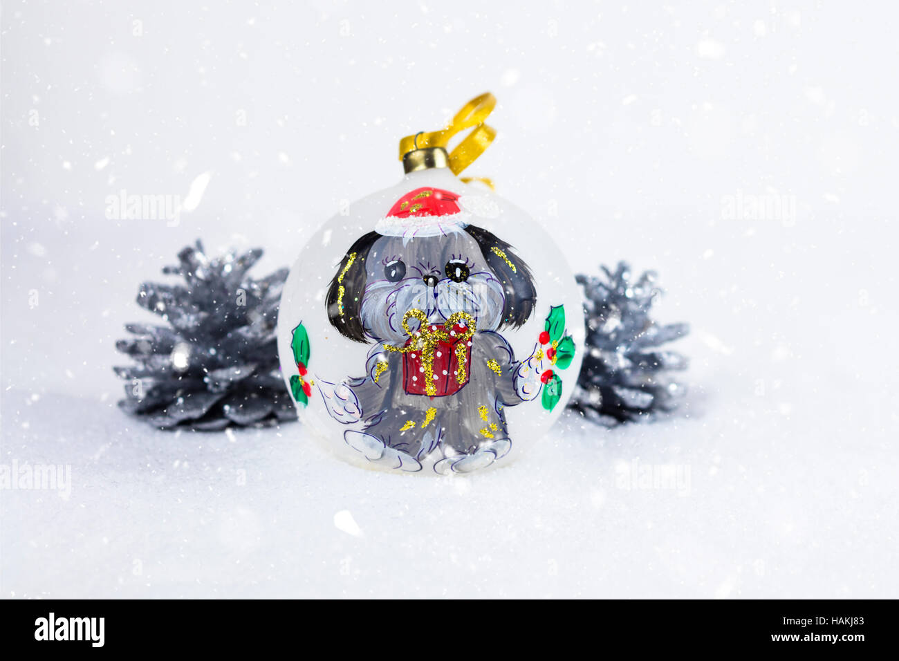 Pallina di natale con il disegno di un cane e di pini su un bianco della neve sullo sfondo. Foto Stock