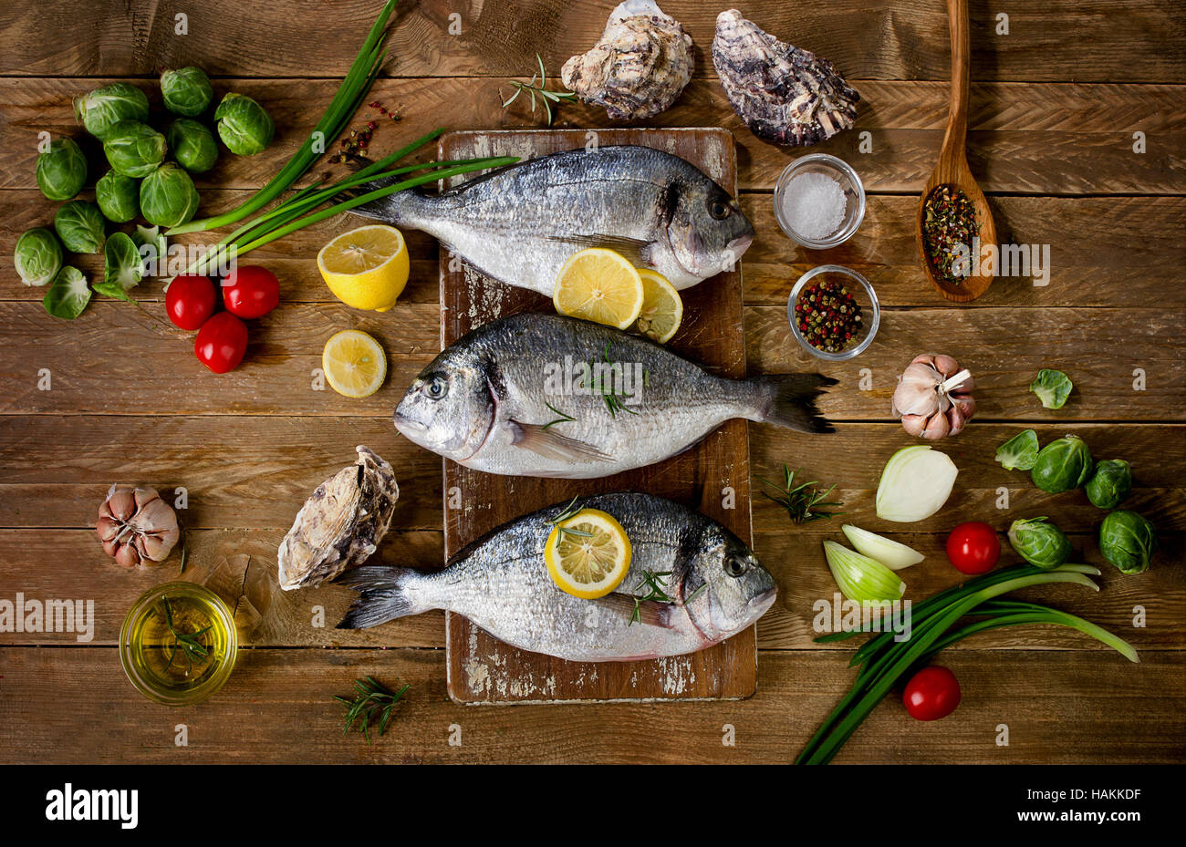Pesce fresco con erbe aromatiche, spezie e verdure su sfondo di legno. Cibo sano concetto. Vista superiore Foto Stock