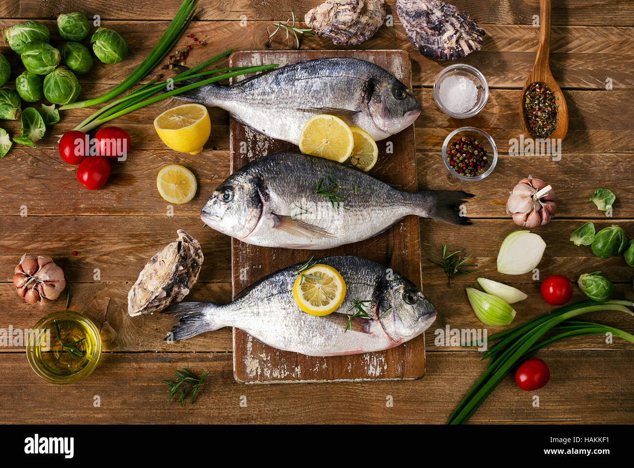 Pesce fresco con erbe aromatiche, le spezie e le verdure su uno sfondo di legno. Cibo sano concetto. Vista superiore Foto Stock