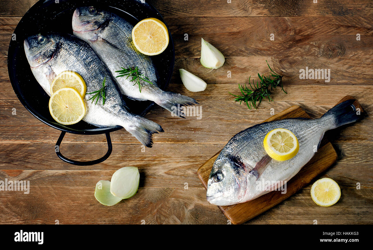 Pesce fresco con erbe su un tavolo di legno. Una dieta salutare concetto. Vista superiore Foto Stock