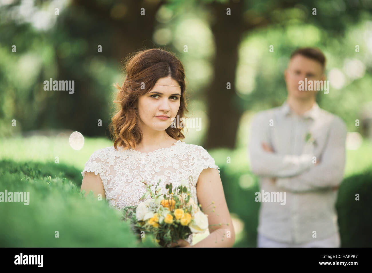 Sposa in posa e sorrisi mentre lo sposo attende sullo sfondo Foto Stock
