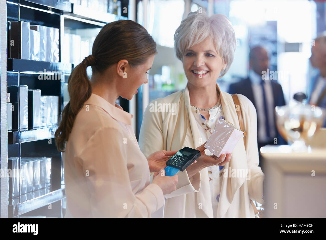 Donna acquisto di profumo in negozio dal cancelliere con la connessione wireless con il lettore di carte di credito Foto Stock