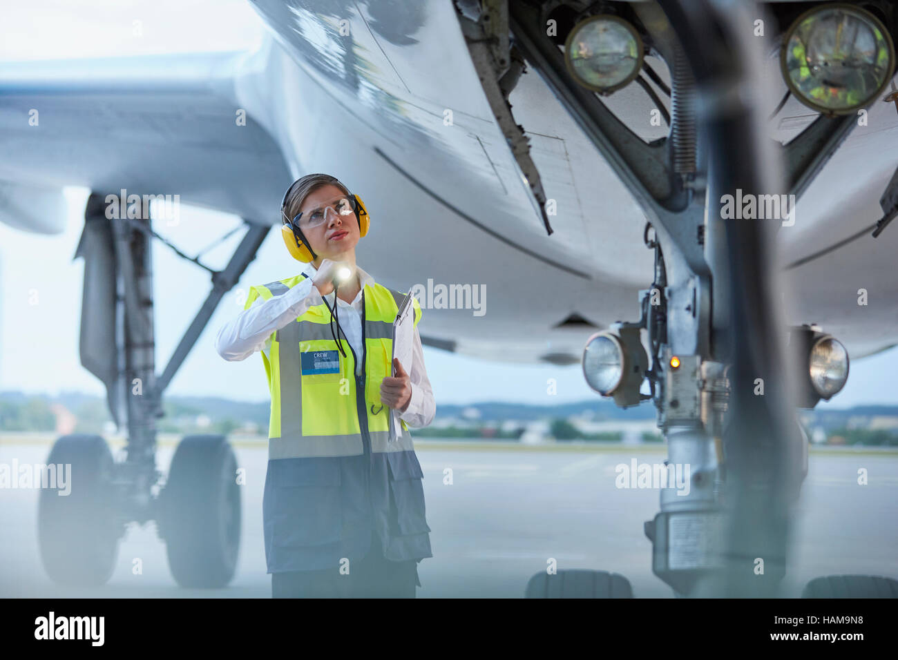 Personale di terra lavoratore sotto aereo con torcia al aeroporto di asfalto Foto Stock