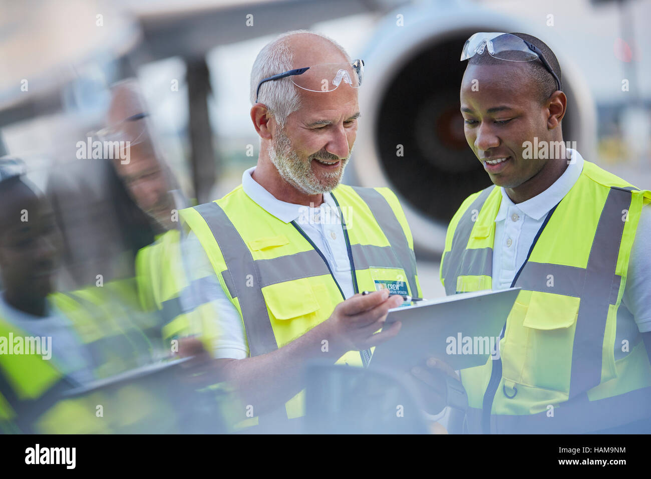 Il controllo del traffico aereo a terra i lavoratori di equipaggio di parlare con tavoletta digitale su airport tarmac Foto Stock