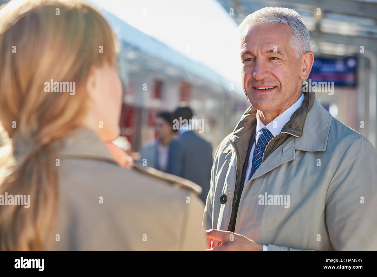 Imprenditore parlando di imprenditrice sulla stazione ferroviaria platform Foto Stock